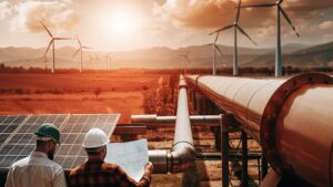 Engineers reviewing plans at a renewable energy site with solar panels, wind turbines, and industrial pipelines — representing Taiyo Holding’s EPC Excellence.